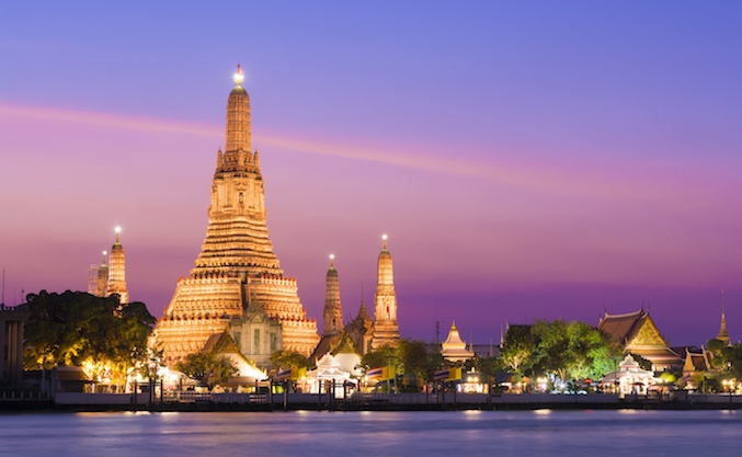 The illuminated temple of Wat Arun on the Chao Phraya river at sunset in Bangkok, Thailand