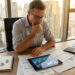 Un homme d'affaires réfléchi examinant des données financières sur une tablette face à une vue urbaine.