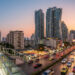 Une passerelle piétonne surplombant une rue animée de Sukhumvit à Bangkok au coucher du soleil avec des gratte-ciels.