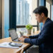 Un homme en costume travaillant sur un ordinateur portable dans un bureau moderne avec vue sur la ville.