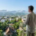 Un homme sur un balcon surplombant Chiang Mai avec une tablette, analysant des données immobilières.