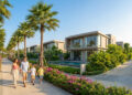 Une famille heureuse se promène dans une résidence moderne avec palmiers, villas avec piscine et jardins fleuris.