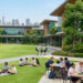 Élèves en uniforme sur le campus verdoyant d'une école internationale avec les gratte-ciel de Bangkok en arrière-plan.