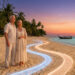Couple de retraités sur une plage tropicale au coucher du soleil avec deux chemins lumineux symboliques au sol.