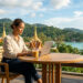 Femme travaillant sur son ordinateur portable sur une terrasse surplombant une baie thaïlandaise avec des temples.