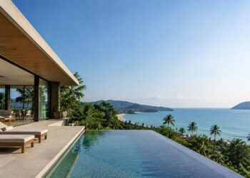 Une villa moderne avec piscine à débordement donnant sur une plage tropicale et l'océan en Thaïlande.