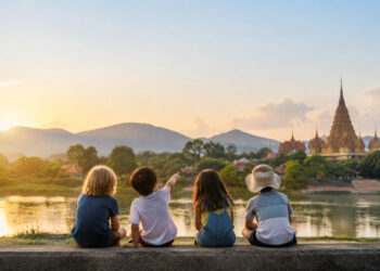 Quatre enfants assis côte à côte regardant un temple thaï au coucher du soleil.