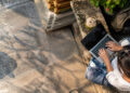 Vue de dessus d'une personne travaillant sur un ordinateur portable à côté d'une noix de coco en Thaïlande.