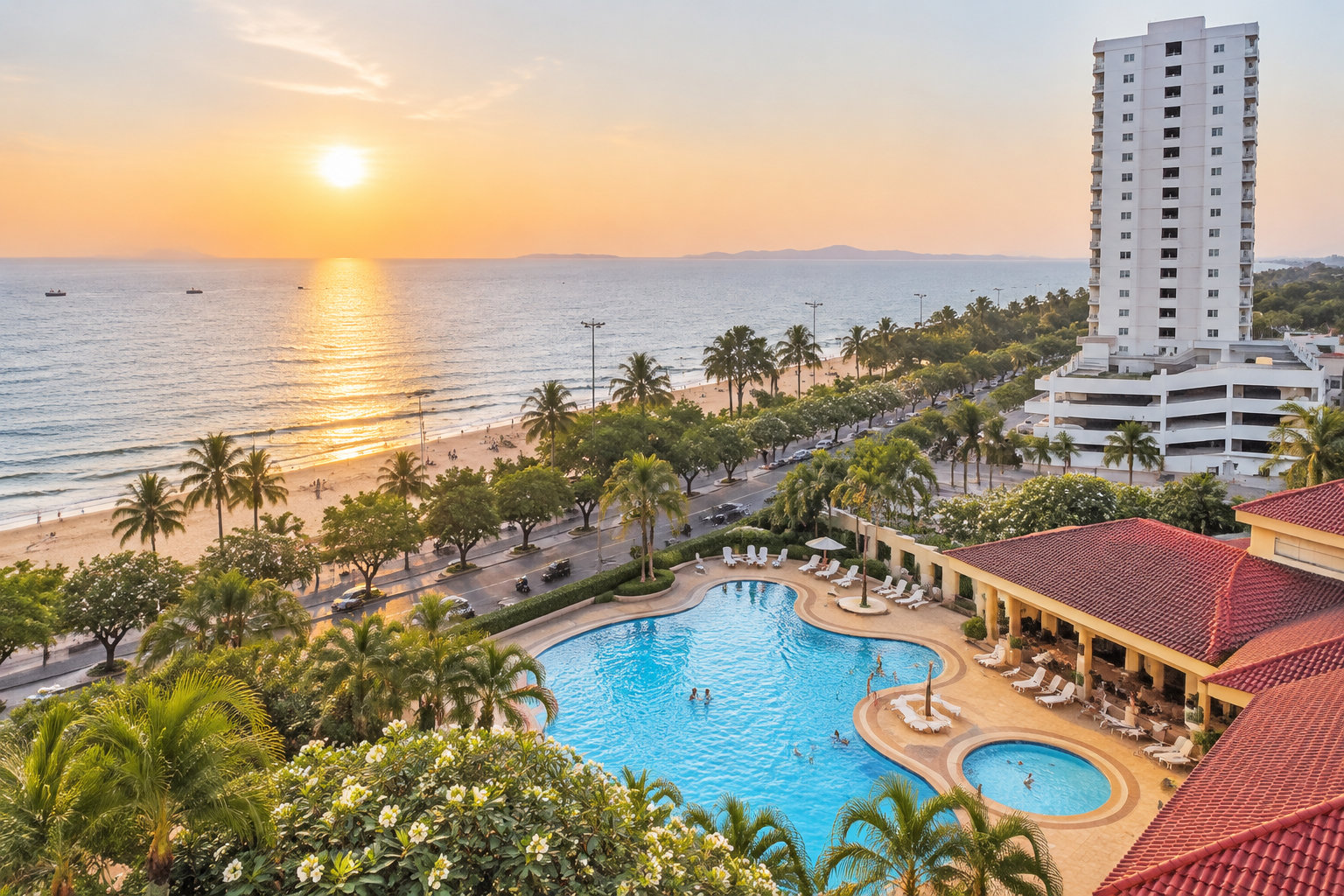 Une piscine bordée de palmiers et de bâtiments surplombe une plage et la mer au coucher du soleil.